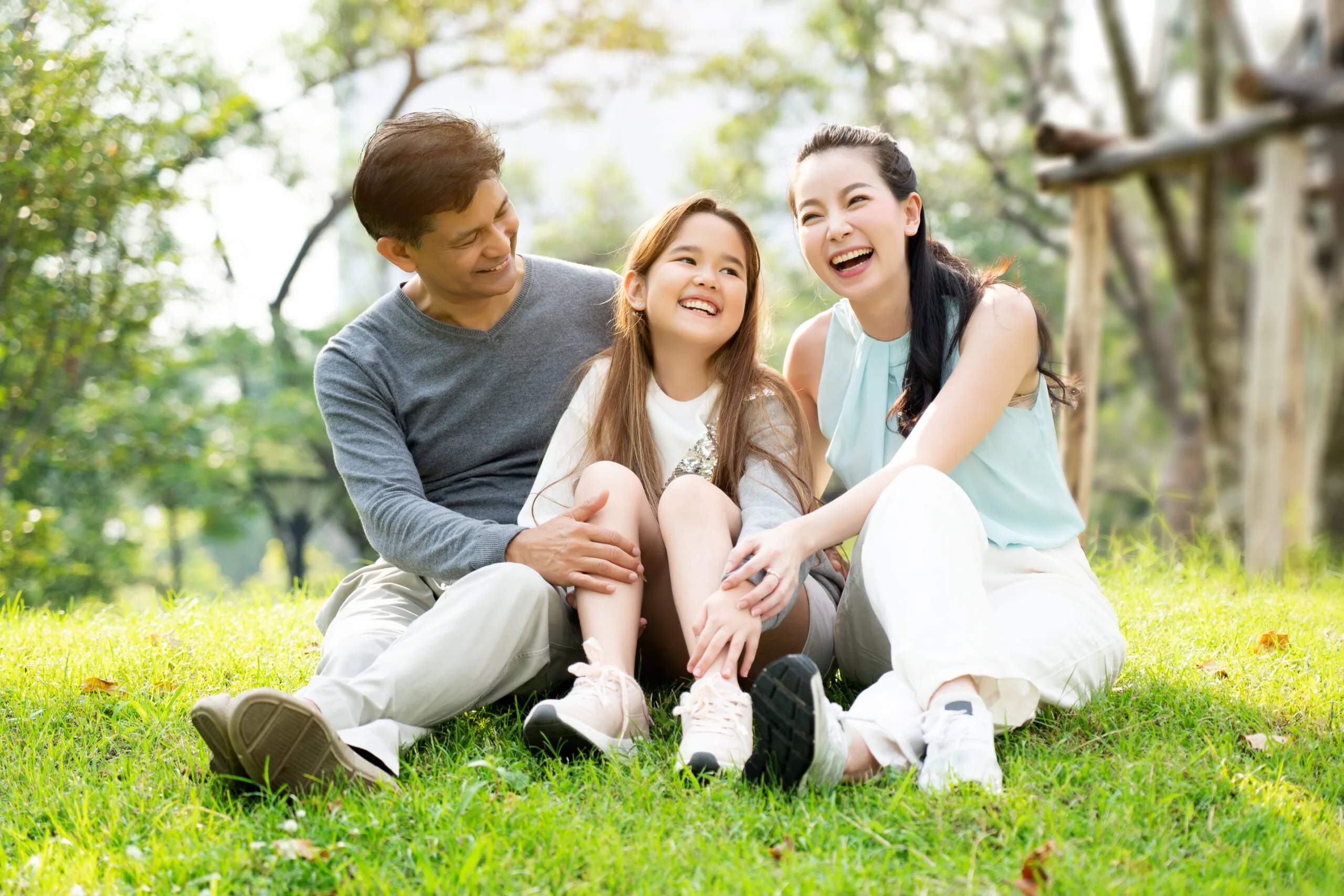 a family of 3 hanging out in a green park